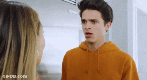 A Young Man In An Orange Hoodie Talks To A Young Woman GIF