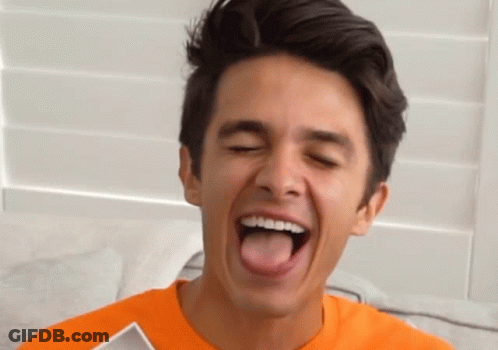 A Young Man In An Orange Shirt Sticks His Tongue Out GIF