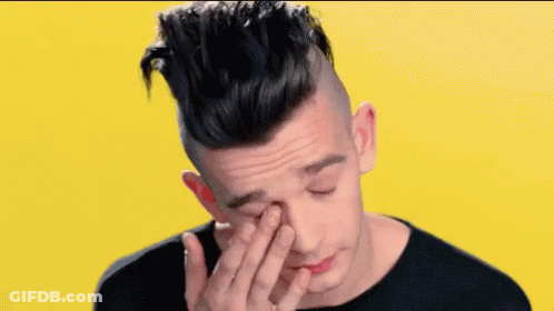 A Young Man Is Covering His Face With His Hand . GIF