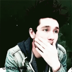A Young Man Is Covering His Mouth With His Hand . GIF