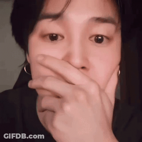 A Young Man Is Covering His Mouth With His Hand . GIF