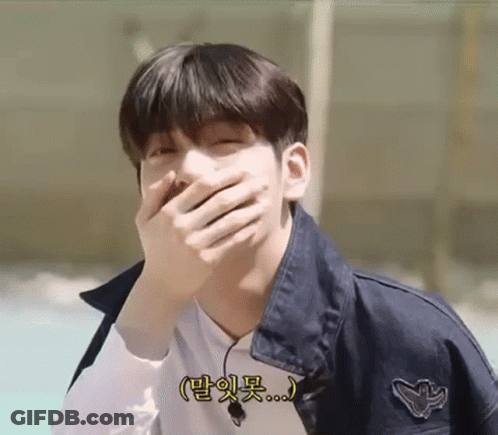 A Young Man Is Covering His Mouth With His Hand And Smiling . GIF