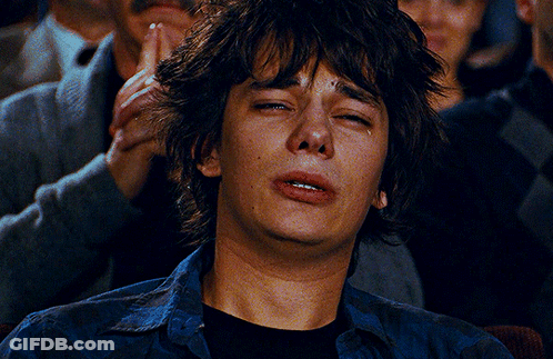 A Young Man Is Crying While Sitting In A Crowd Of People GIF