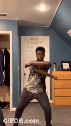 A Young Man Is Dancing In A Room With A Blue Wall And A Dresser . GIF