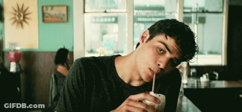 A Young Man Is Drinking A Milkshake Through A Straw . GIF