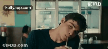 A Young Man Is Drinking Through A Straw In A Restaurant . GIF
