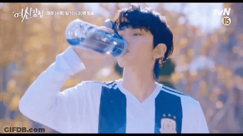 A Young Man Is Drinking Water From A Bottle . GIF