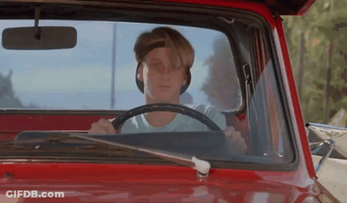 A Young Man Is Driving A Red Truck With The Hood Open . GIF