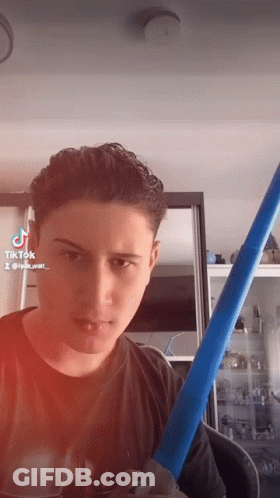 A Young Man Is Holding A Blue Mop And Looking At The Camera With Tiktok Written On The Bottom Of The Screen GIF