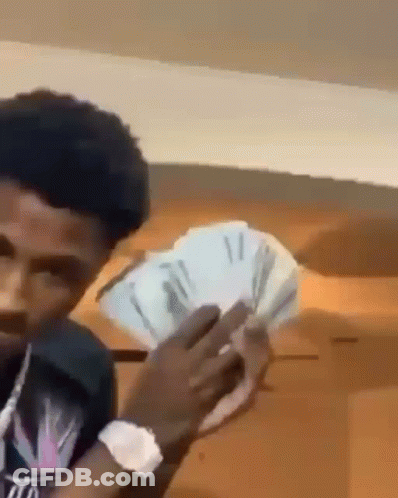 A Young Man Is Holding A Bunch Of Money In His Hands . GIF