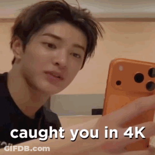 A Young Man Is Holding A Cell Phone In His Hand . GIF