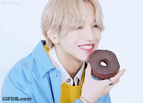 A Young Man Is Holding A Chocolate Donut In His Hand . GIF