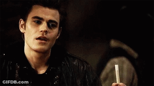 A Young Man Is Holding A Cigarette In His Hand And Smoking It . GIF