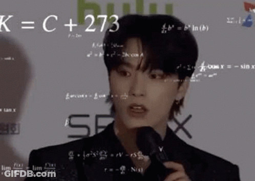 A Young Man Is Holding A Microphone In Front Of A Wall With Math Equations On It . GIF