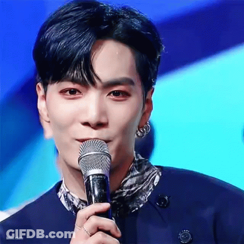 A Young Man Is Holding A Microphone In His Hand And Talking Into It . GIF