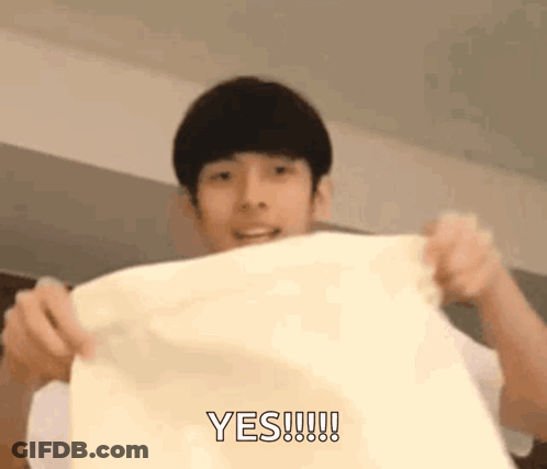 A Young Man Is Holding A Piece Of Paper In His Hands And Says Yes . GIF