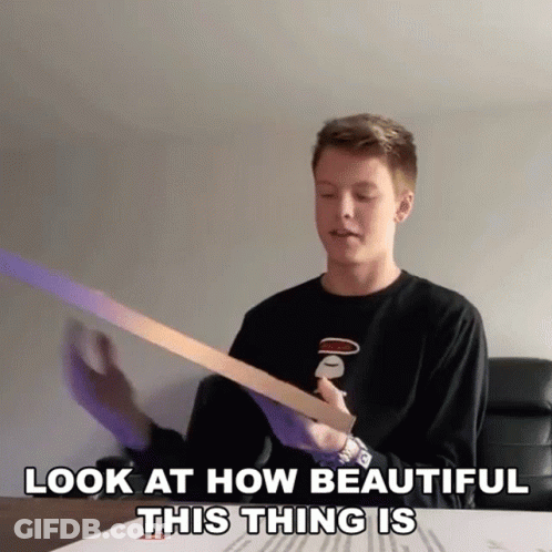 A Young Man Is Holding A Piece Of Paper With The Words Look At How Beautiful This Thing Is Below Him GIF