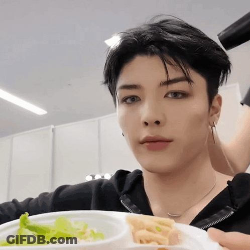 A Young Man Is Holding A Plate Of Food With A Salad And French Fries On It GIF