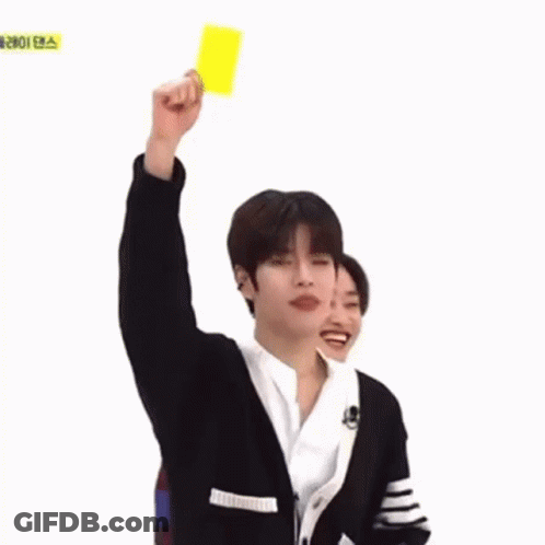 A Young Man Is Holding Up A Yellow Card In A Foreign Language . GIF