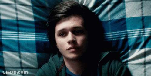 A Young Man Is Laying On A Bed With A Blue And White Plaid Blanket GIF