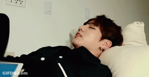 A Young Man Is Laying On A Bed With His Head On A Pillow GIF