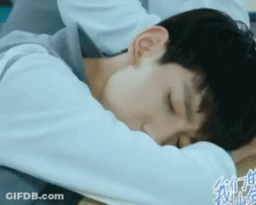 A Young Man Is Laying On A Bed With His Head On His Arm . GIF