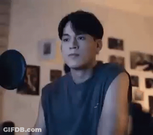 A Young Man Is Lifting A Dumbbell In A Room . GIF