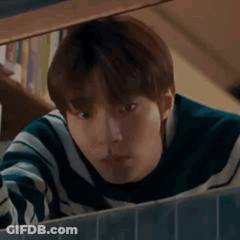 A Young Man Is Looking Out Of A Window . GIF