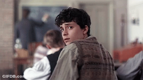 A Young Man Is Looking Over His Shoulder In A Classroom . GIF