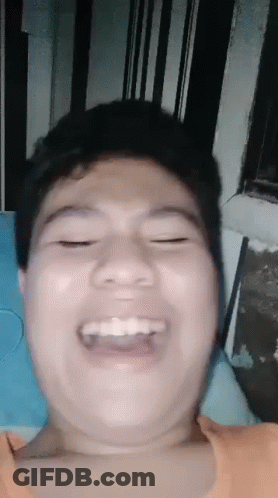 A Young Man Is Making A Funny Face While Laying On A Bed . GIF