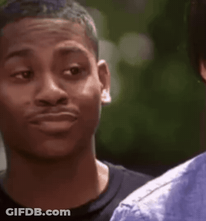 A Young Man Is Making A Funny Face While Looking At Another Man . GIF