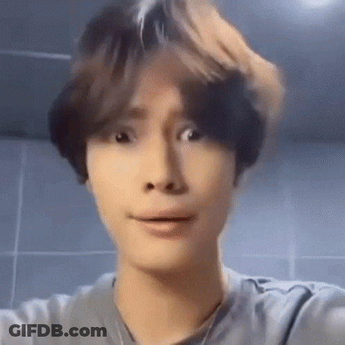 A Young Man Is Making A Funny Face While Taking A Selfie In Front Of A Mirror . GIF