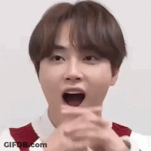 A Young Man Is Making A Funny Face With His Mouth Open And His Hands Folded . GIF