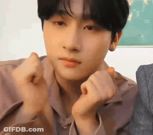 A Young Man Is Making A Heart Shape With His Hands While Looking At The Camera . GIF