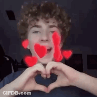 A Young Man Is Making A Heart With His Hands . GIF