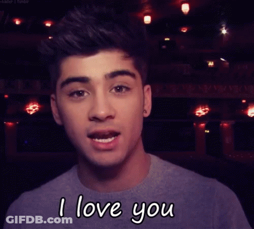 A Young Man Is Saying I Love You In Front Of A Dark Background GIF