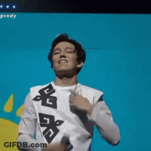 A Young Man Is Singing Into A Microphone On A Stage And Dancing . GIF