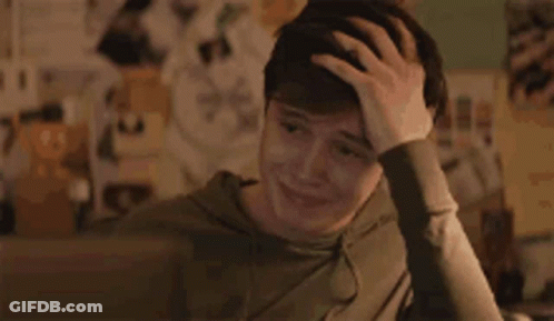 A Young Man Is Sitting At A Desk Holding His Head . GIF