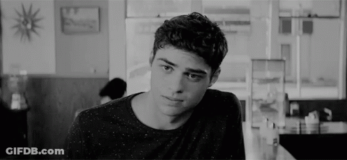 A Young Man Is Sitting At A Table In A Diner Looking At The Camera . GIF