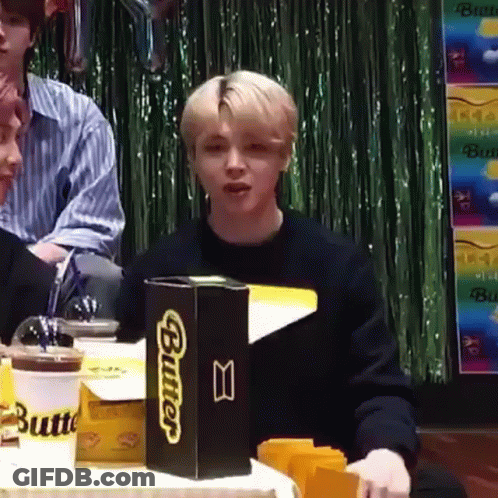 A Young Man Is Sitting At A Table With A Box Of Butter . GIF