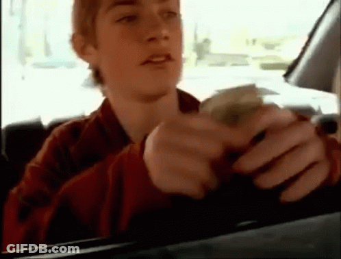 A Young Man Is Sitting In A Car Holding A Bunch Of Money . GIF