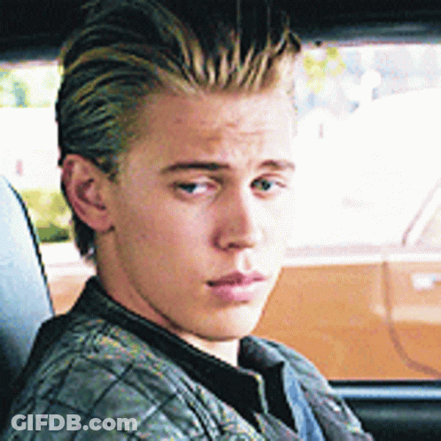 A Young Man Is Sitting In A Car Looking Out The Window GIF