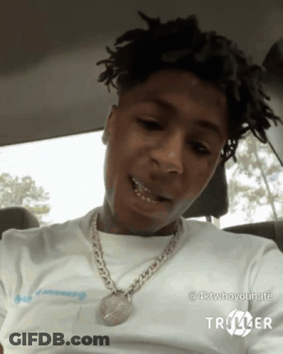 A Young Man Is Sitting In A Car Wearing A White Shirt And A Chain . GIF