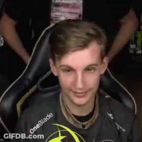A Young Man Is Sitting In A Chair And Smiling While Wearing A Oneblade Shirt . GIF