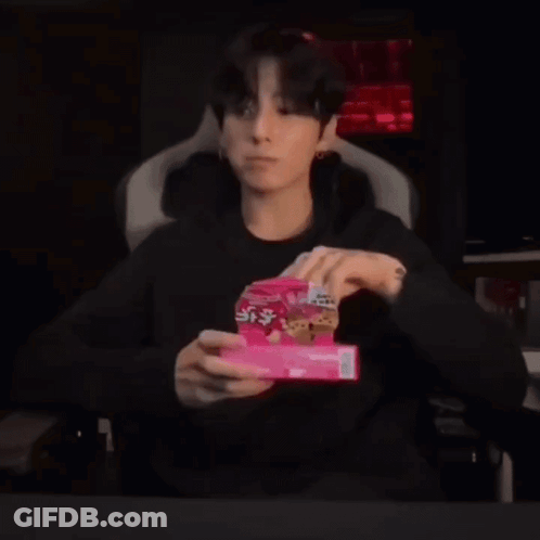 A Young Man Is Sitting In A Chair Holding A Box Of Cookies In His Hands . GIF