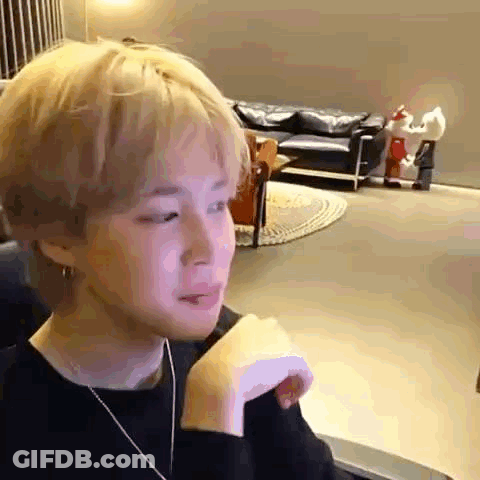 A Young Man Is Sitting In A Chair In A Living Room With His Hand On His Shoulder . GIF