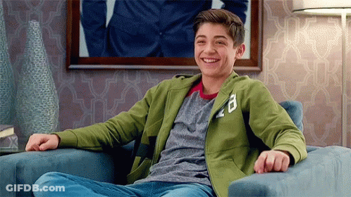 A Young Man Is Sitting In A Chair Smiling . GIF