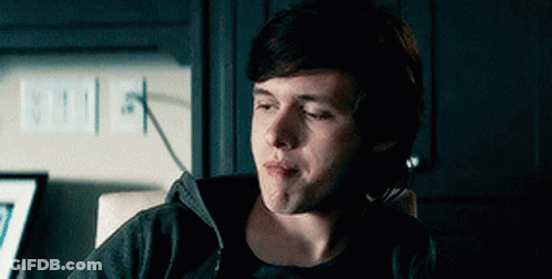 A Young Man Is Sitting In A Chair With His Eyes Closed And Making A Funny Face . GIF
