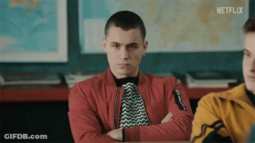 A Young Man Is Sitting In A Classroom With His Arms Crossed . GIF