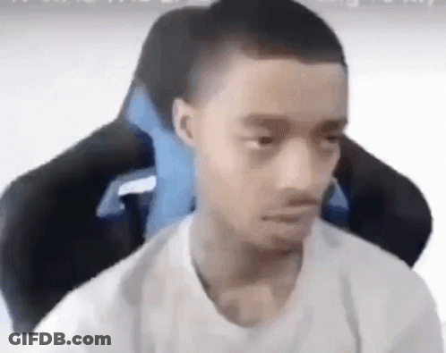 A Young Man Is Sitting In A Gaming Chair With A Blue Pillow . GIF